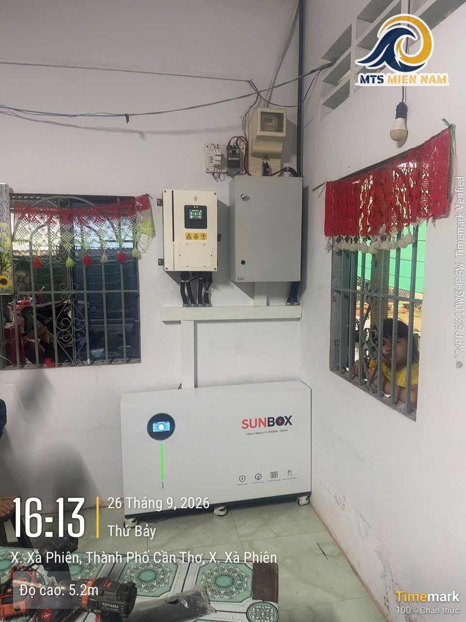 Hộ gia đình tại xã Xà Phiên – 09/2026 – Dàn pin trên mái tôn, biến tần hybrid và pin lưu trữ SUNBOX; chủ nhà xem sản lượng qua ứng dụng.